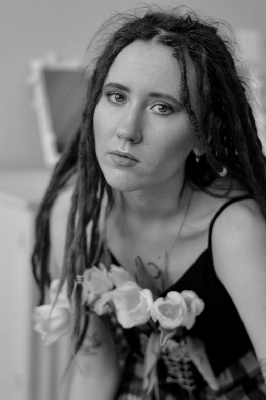 a black and white photo of a woman with dreadlocks, a black and white photo, inspired by Billie Waters, sitting with flowers, loving stare, waist up portrait, maiden with copper hair