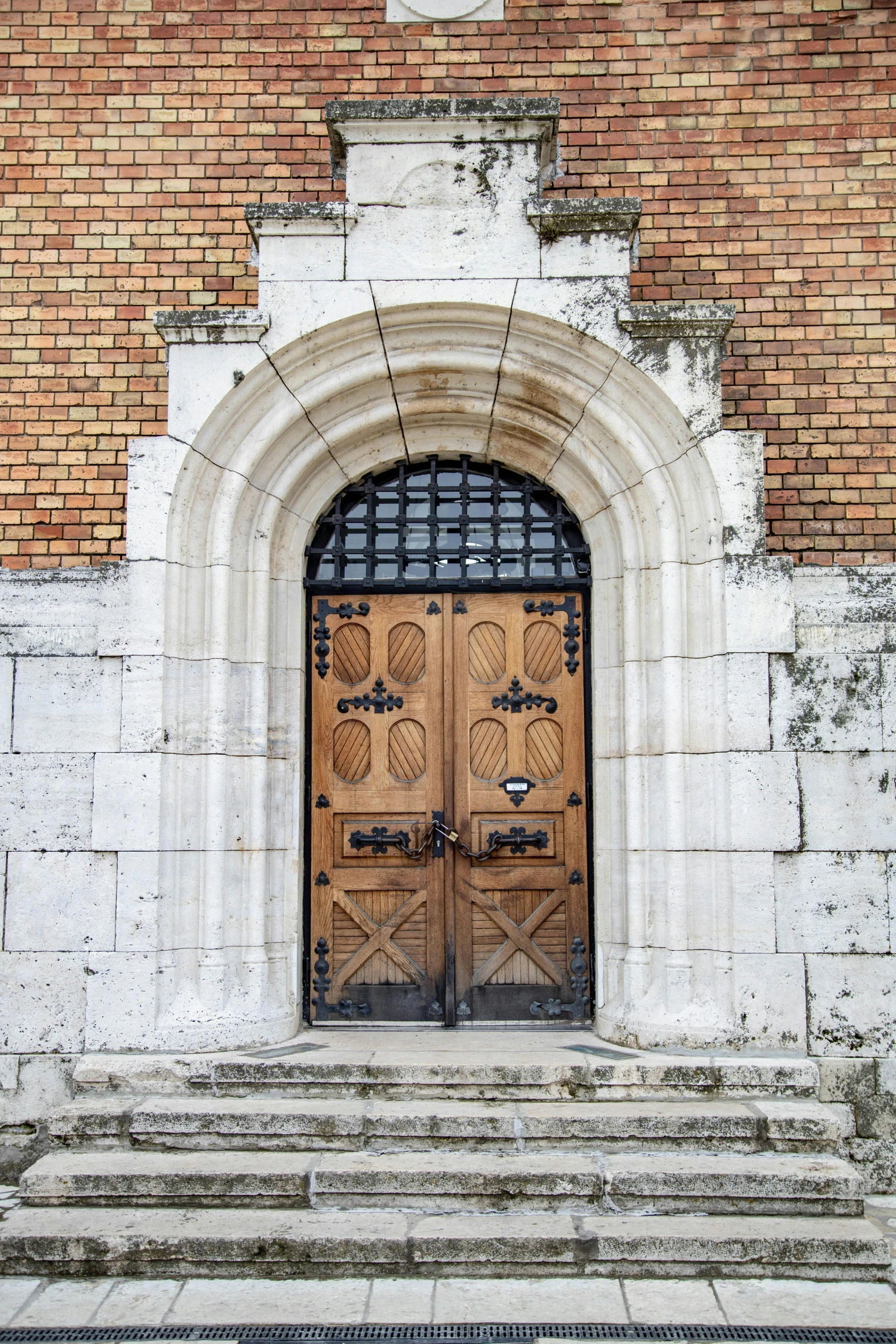 a red fire hydrant sitting in front of a brick building, an album cover, romanesque, arched doorway, london cemetery, brown, wood door