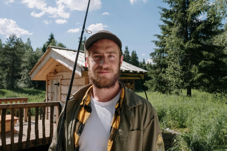 a man standing in front of a cabin holding a fishing rod, a portrait, inspired by Jóhannes Sveinsson Kjarval, pexels contest winner, portrait of chris evans, low quality photo, pewdiepie