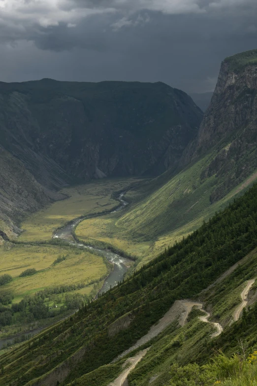 a view of a valley from the top of a mountain, by Muggur, river running through it, very dramatic light, astri lohne