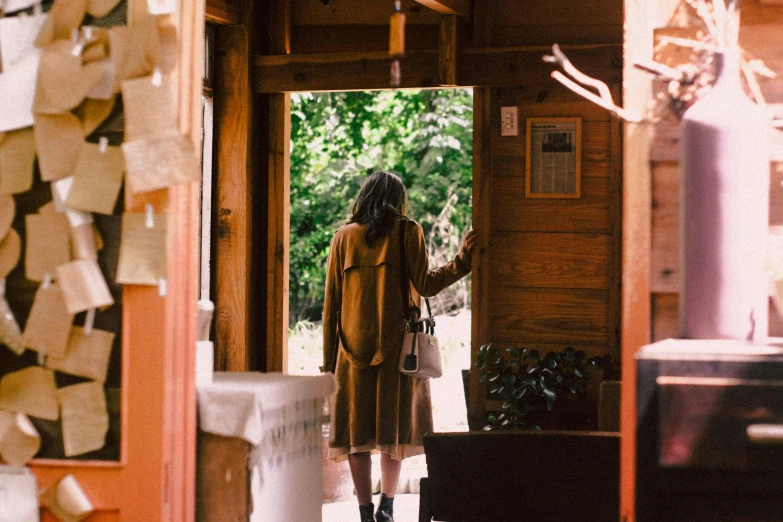 a woman standing in the doorway of a house, unsplash, visual art, in karuizawa, brown, cabin, people walking around