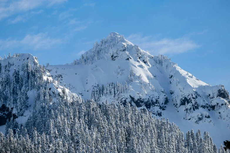 a man riding skis down a snow covered slope, by Jim Nelson, trending on unsplash, giant imposing mountain, black fir, thumbnail, high detail photo