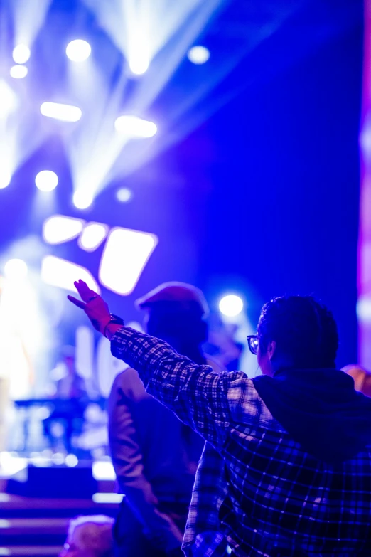 a group of people standing in front of a stage, pexels, happening, listening to godly music, blue and purple lighting, jesus wasted at a party, worshipers