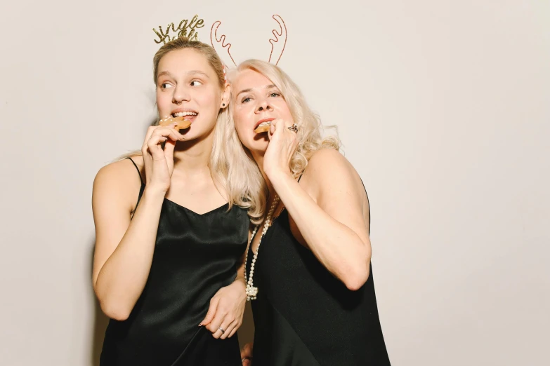 a couple of women standing next to each other, a photo, pexels, realism, new years eve, eating, wearing crown, blond