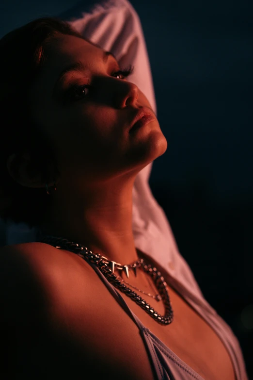 a woman laying on top of a bed under a blanket, an album cover, inspired by Elsa Bleda, trending on pexels, neck chains, evening lighting, profile image, wearing choker