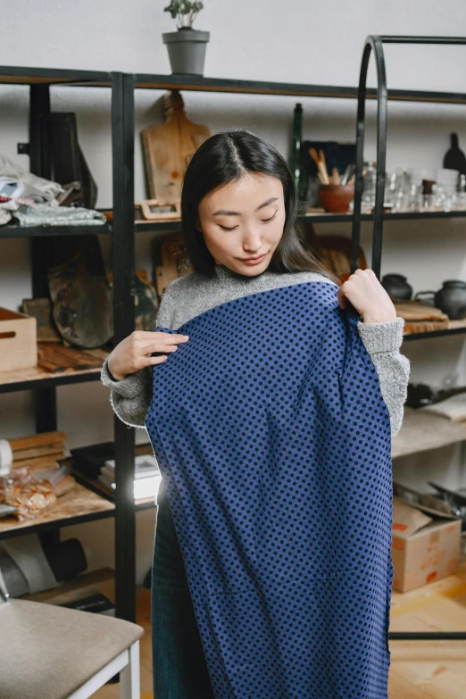 a woman holding a blue blanket in a room, wearing a designer top, carefully crafted, gemma chen, inspect in inventory image