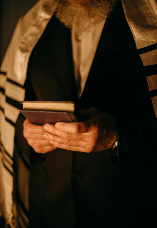 a close up of a person holding a book, religious robes, hebrew, digital still, trending photo