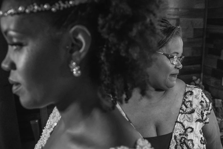 a couple of women standing next to each other, a black and white photo, by Dan Frazier, bejewelled and encrusted royalty, recital, maternal photography 4 k, thoughtful