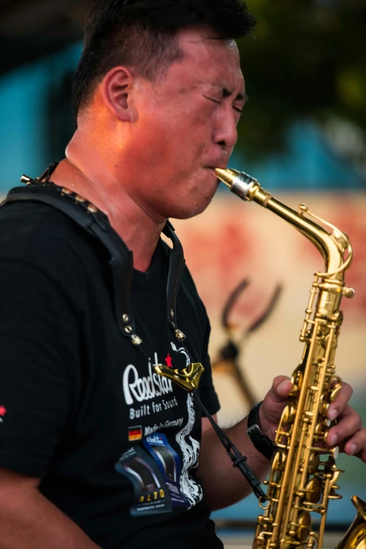a man in a black shirt playing a saxophone, inspired by Guo Chun, neck zoomed in, street life, on stage, blues