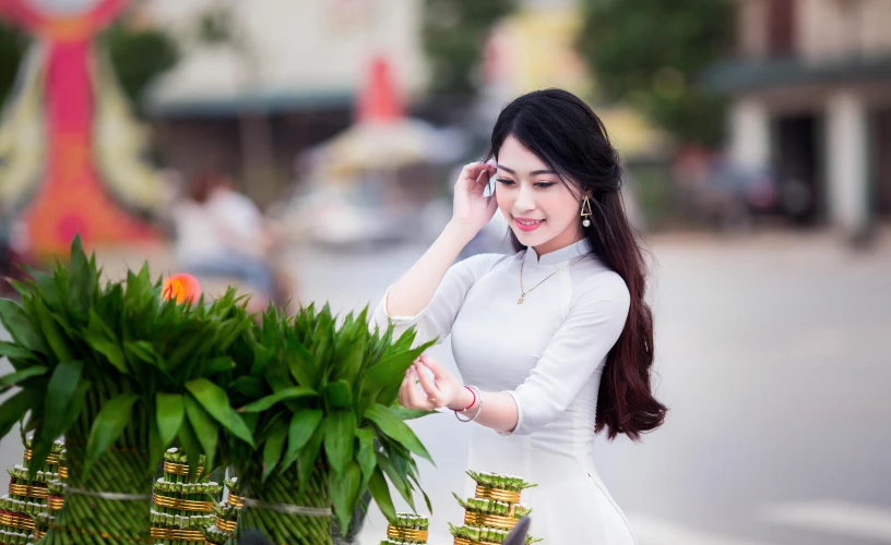 a woman in a white dress standing next to a potted plant, inspired by Tan Ting-pho, pexels contest winner, happening, ao dai, background image, street pic, square