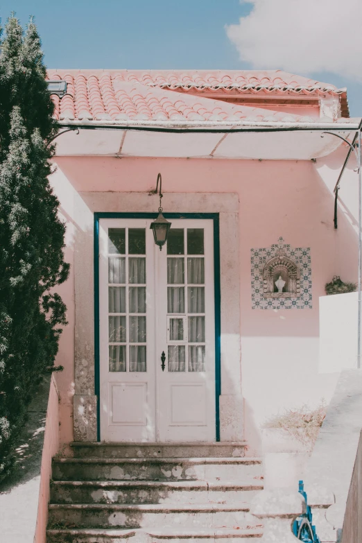 a bicycle parked in front of a pink house, pexels contest winner, rococo, tall door, portugal, white hue, patio