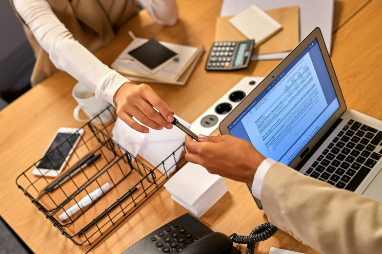 a couple of people sitting at a table with a laptop, at checkout, on paper, loosely cropped, professional image