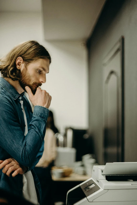 a man that is standing in front of a printer, trending on pexels, renaissance, pensive expression, in a kitchen, mid long hair, pondering