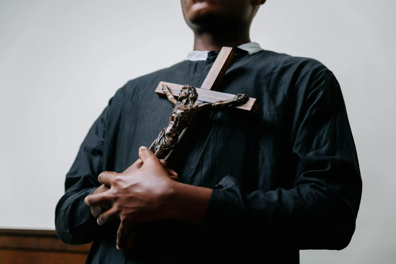 a man holding a wooden cross in his hands, by Matthias Stom, pexels contest winner, hurufiyya, black robe, thumbnail, brown, servants