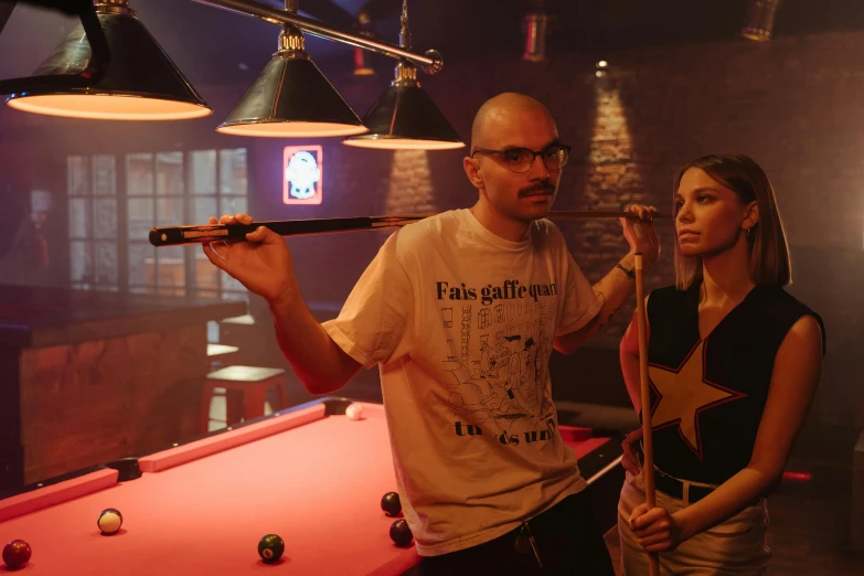 a man and a woman standing next to a pool table, a portrait, pexels, antipodeans, film still of gal gadot, anya_taylor-joy, shaved head, twitch streamer / gamer ludwig