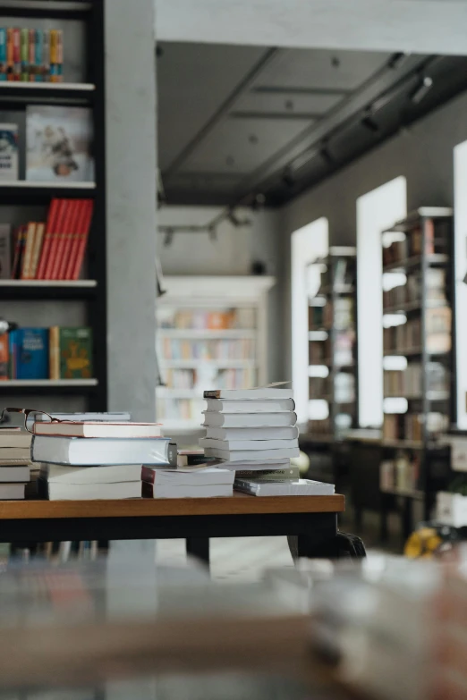 a pile of books sitting on top of a wooden table, spiral shelves full of books, stores, front facing