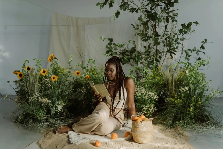 a woman sitting on a blanket reading a book, a portrait, by Carey Morris, pexels contest winner, with fruit trees, black african princess, plants and flowers, performing