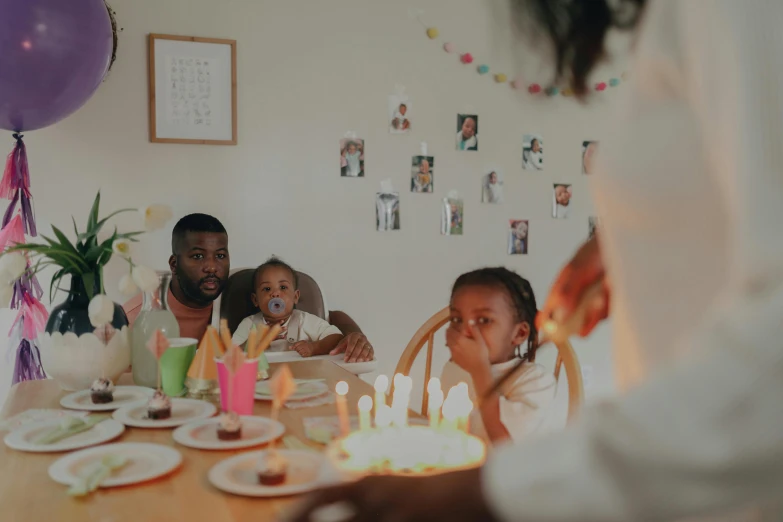 a group of people sitting around a table at a birthday party, by Emma Andijewska, pexels contest winner, hyperrealism, fatherly, black people, promotional image, thumbnail