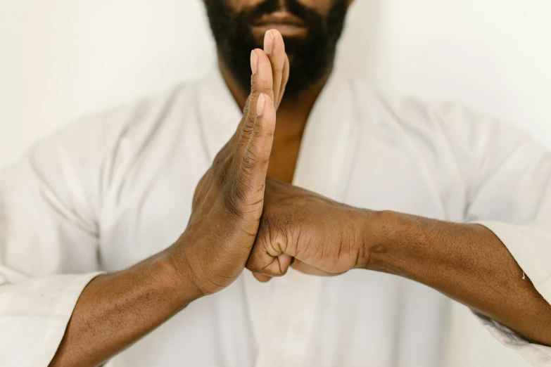 a man in a white shirt doing a yoga pose, inspired by Ma Quan, unsplash, detailed and realistic hands, man is with black skin, wearing brown robes, pointing