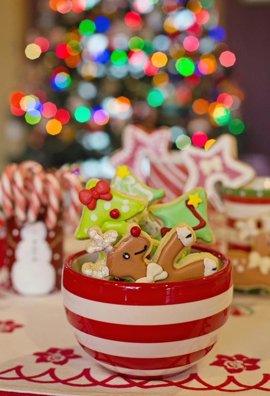 a bowl of cookies on a table with a christmas tree in the background, by Julia Pishtar, pexels, sanrio ornaments, brightly lit!, candy canes, studio photo