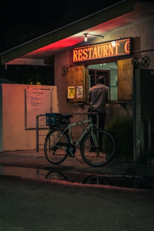 a man standing outside of a restaurant at night, by Adam Rex, pexels contest winner, realism, bicycle, diner food, settlement, afternoon