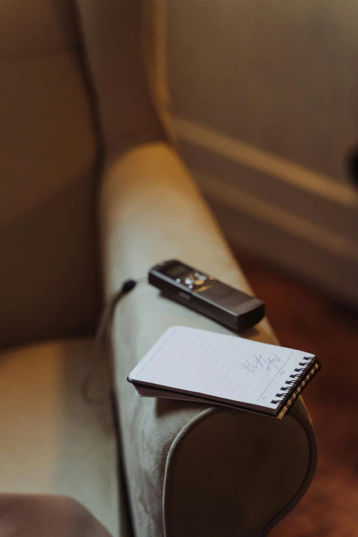 a notepad sitting on top of a couch next to a remote control, unsplash, shot on hasselblad, thoughtful, high quality photo, medium-shot