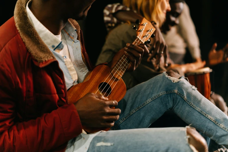 a man that is sitting down with a guitar, by Matija Jama, trending on pexels, mix of ethnicities and genders, ukulele, a group of people, holding an epée