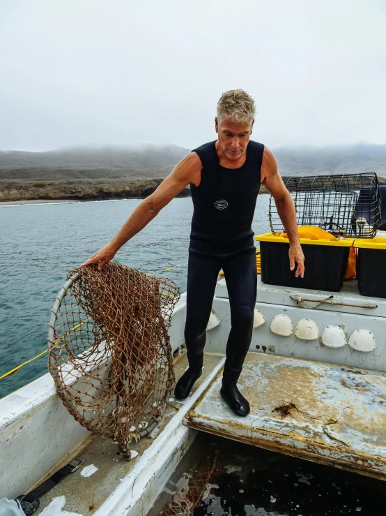 a man standing on top of a boat holding a net, gordon ramsay, kelp, slightly tanned, reefs