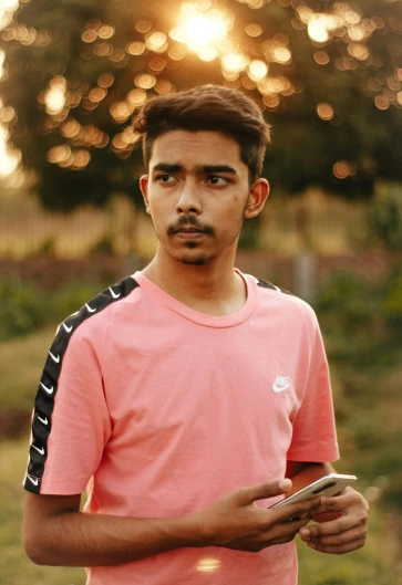 a man in a pink shirt holding a cell phone, by Max Dauthendey, trending on dribble, he is about 20 years old | short, jayison devadas, portait photo profile picture, trending on tiktok