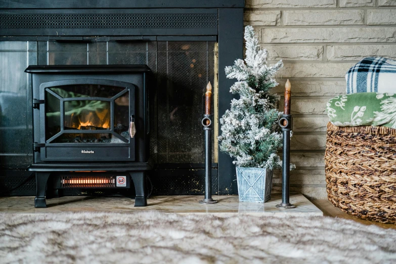 a fireplace with a potted christmas tree next to it, himalayan rocksalt lamp, cannon snow covered trees, full product shot, ashford black marble