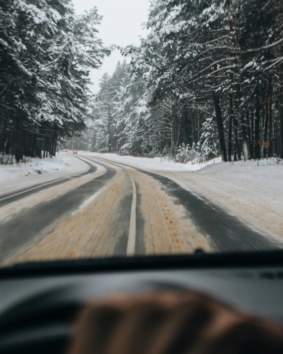 a person driving a car on a snowy road, trees in the background, portrait featured on unsplash, lgbtq, background image