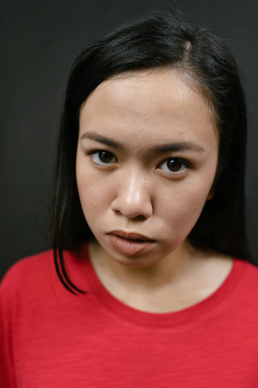 a woman in a red shirt looking at the camera, a character portrait, inspired by Li Tiefu, pexels contest winner, annoyed expression, south east asian with round face, pout, low-key