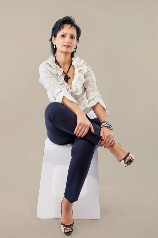 a woman sitting on top of a white stool, wearing elegant casual clothes, very consistent, roxie vizcarra, relaxed posture