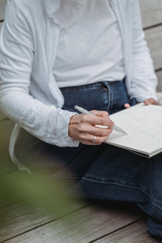 a woman sitting on a bench writing in a notebook, a drawing, inspired by Ruth Jên, trending on unsplash, visual art, wearing a white button up shirt, full body close-up shot, paul barson, 40 years old women