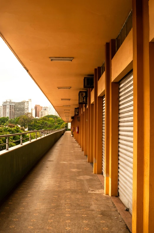 a long walkway with a building in the background, by Joze Ciuha, shops, balcony, shuttered mall store, são paulo