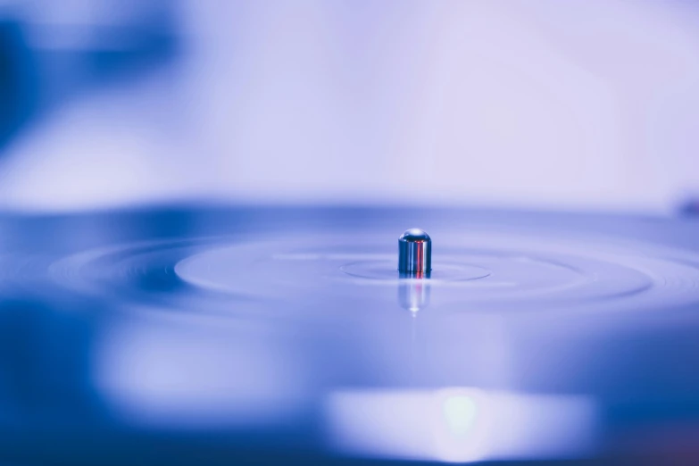 a close up of a record playing on a turntable, an album cover, by Daniel Lieske, unsplash, holography, water droplet, blue and purple, miniature product photo, closeup of magic water gate