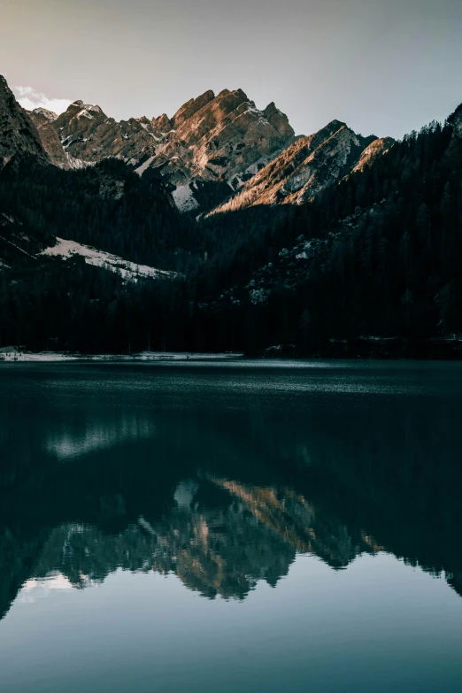 a body of water with mountains in the background, unsplash contest winner, italy, highly reflective light, low light, symmetrical image