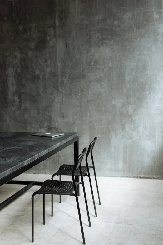 a table and four chairs in a room, by Jan Tengnagel, minimalism, bluestone walls, hay, dark matte metal, architectural digest