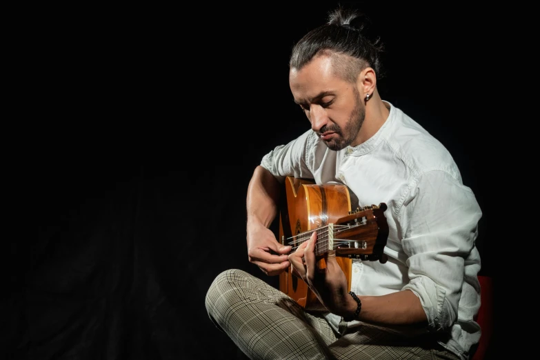 a man sitting on a chair playing a guitar, an album cover, inspired by Cándido López, pexels contest winner, antipodeans, side profile portrait, artem, looking towards camera, performance