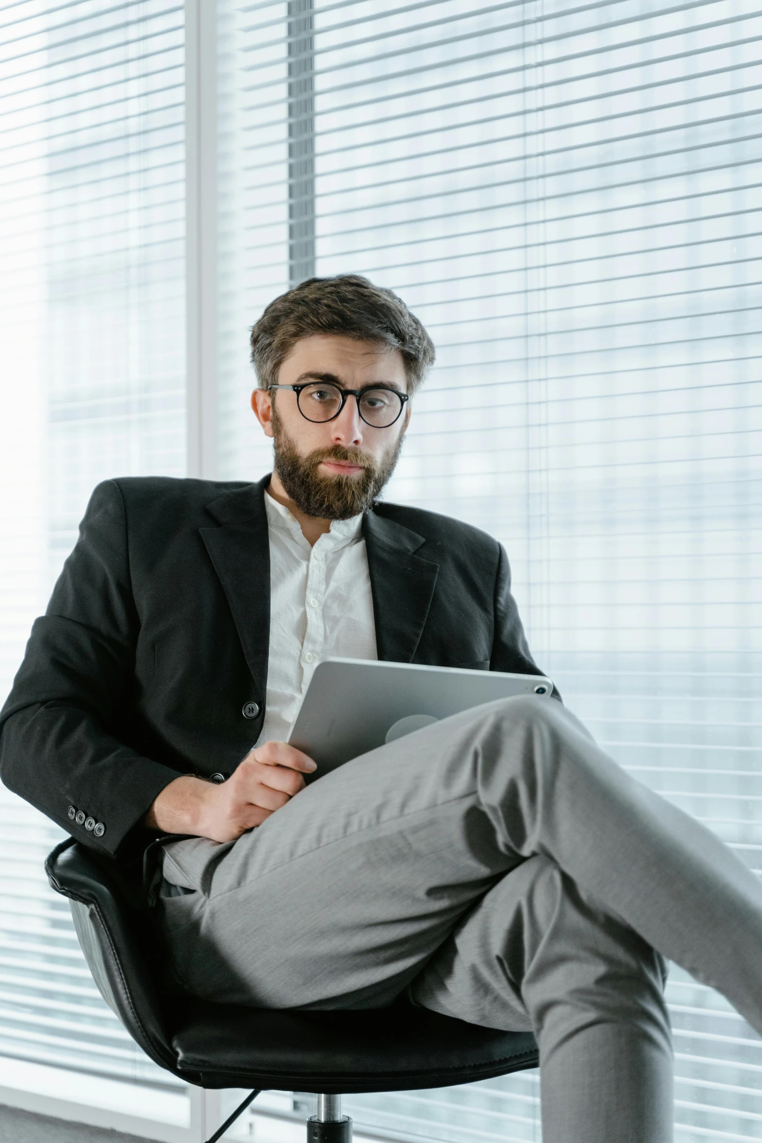 a man sitting in a chair holding a tablet computer, nerdy appearance, sat in an office, 2019 trending photo, looking straight