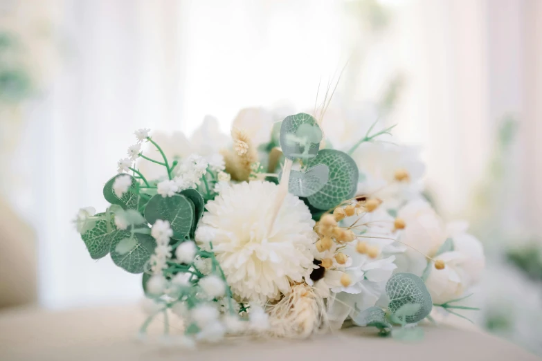 a bouquet of white flowers sitting on top of a table, muted colours, sea green color theme, close up details, on a white table