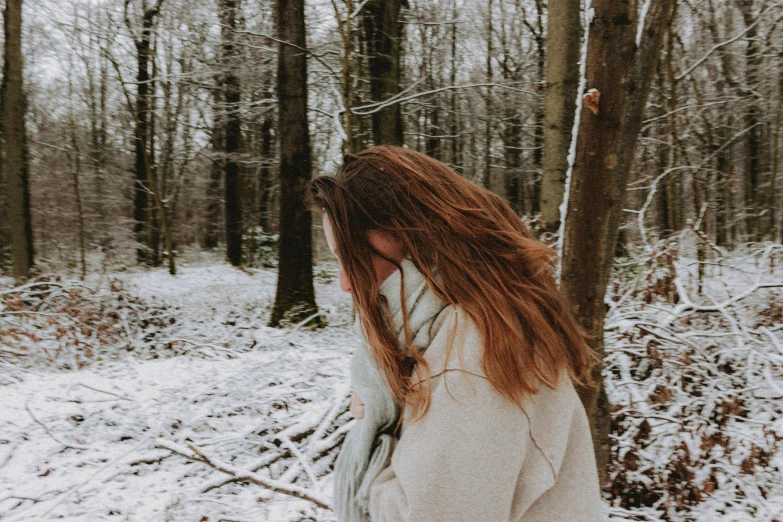 a woman walking through a snow covered forest, trending on pexels, happening, brown messy hair, sad and lonley, background image, colour photo