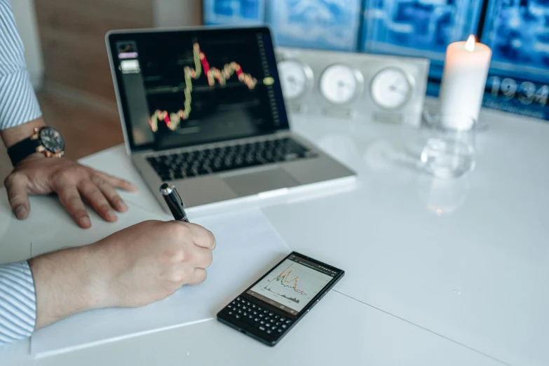 a person sitting at a desk with a cell phone and a laptop, trending on pexels, analytical art, cryptocurrency, maths, thumbnail, mid shot photo