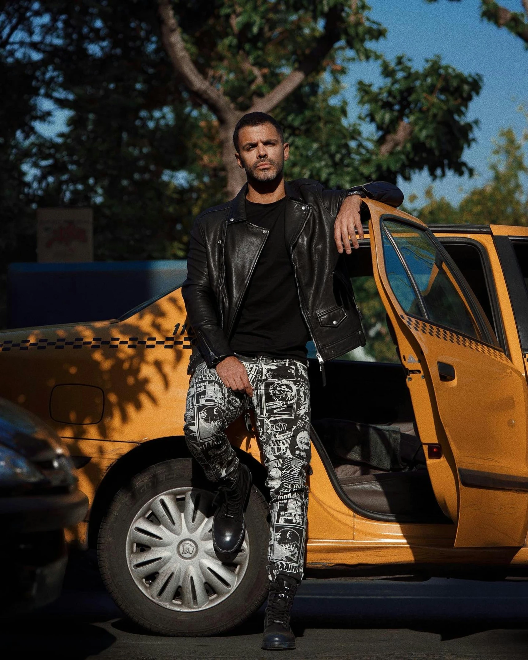 a man standing in front of a yellow taxi, by Adam Saks, leather pants, singer maluma, frank ocean, full body photograph