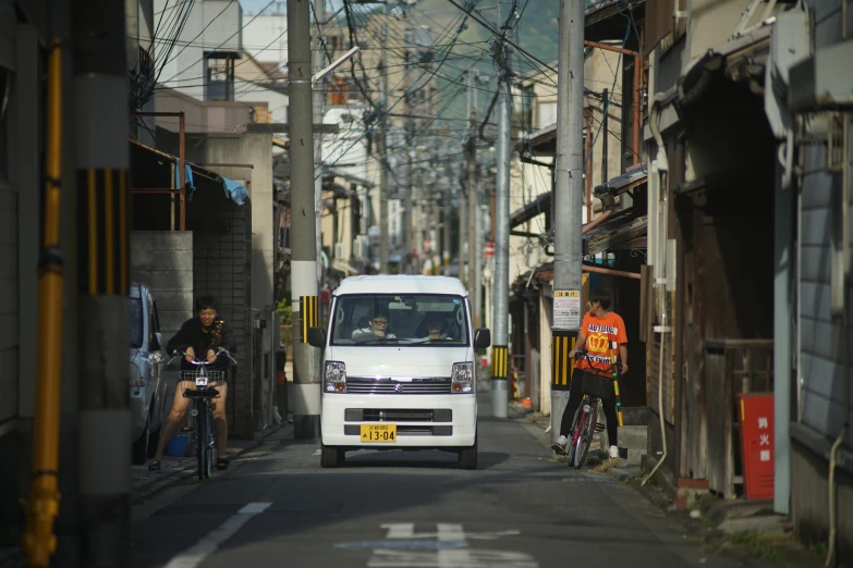 a van that is driving down a street, by Yasushi Sugiyama, unsplash, mingei, in the middle of a small colony, fujifilm”