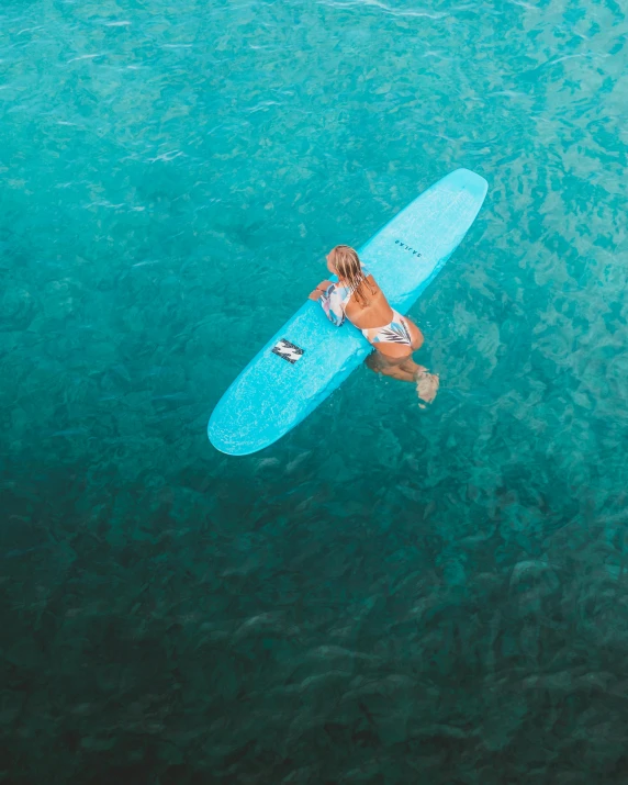 a person laying on a surfboard in the ocean, light blue water, thumbnail, birdseye view, katey truhn