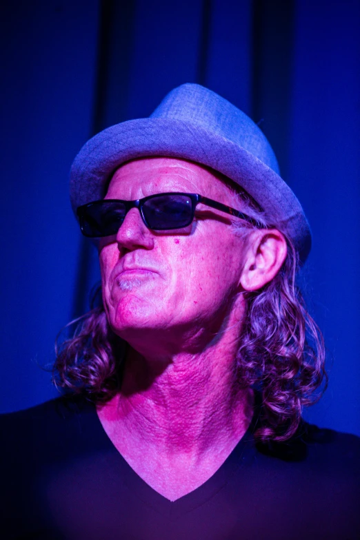 a man with long hair wearing a hat and sunglasses, by Arnie Swekel, low lighting, david noren, half blue, scott adams