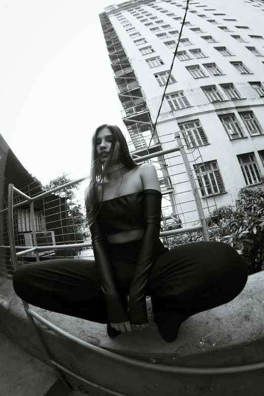 a woman sitting on the ground in front of a building, a black and white photo, unsplash, renaissance, wearing a black bodysuit, wearing a crop top, view from bottom, wearing leather