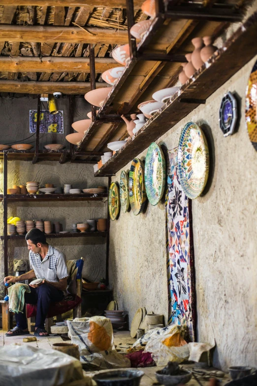 a room filled with lots of plates and bowls, a portrait, inspired by Afewerk Tekle, trending on unsplash, cloisonnism, zhouzhuang ancient town, people at work, hanging, oman