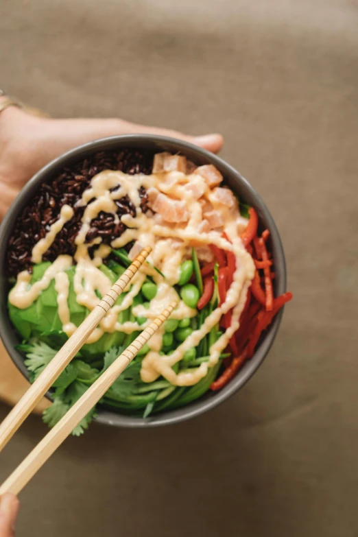 a person holding a bowl of food with chopsticks